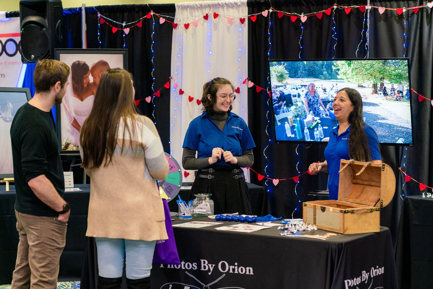 Two women from Photos By Orion talking with two wedding show participants at the Portland Bridal Show.